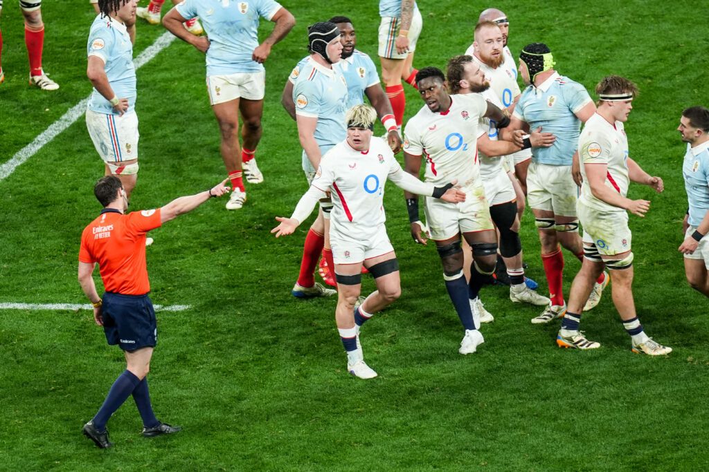 Maro Itoje and Henry Pollock face referee Nika Amashukeli during France v England at the Stade de France