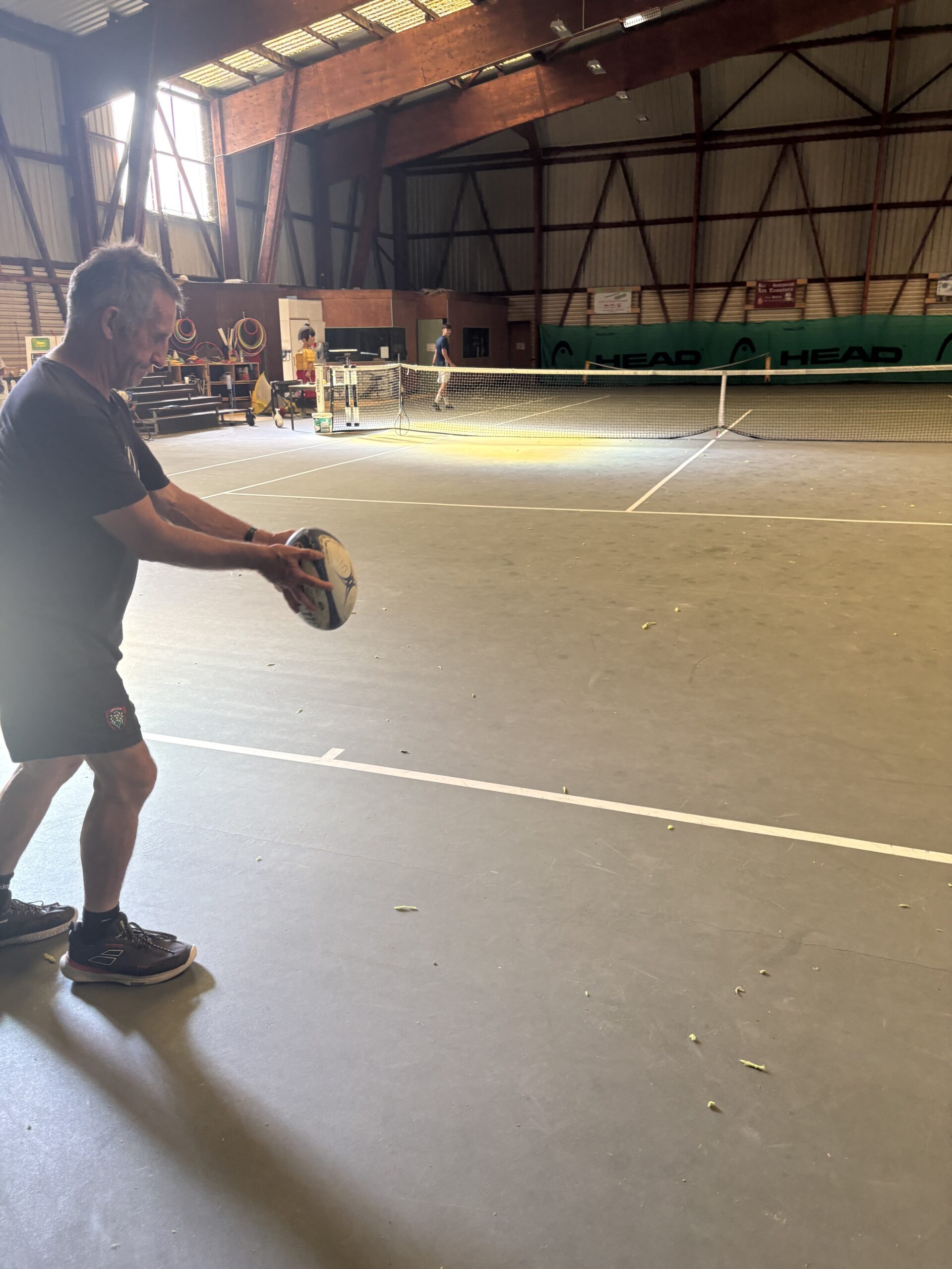 Olivier Miranda about to kick off a rugby ball on a tennis court