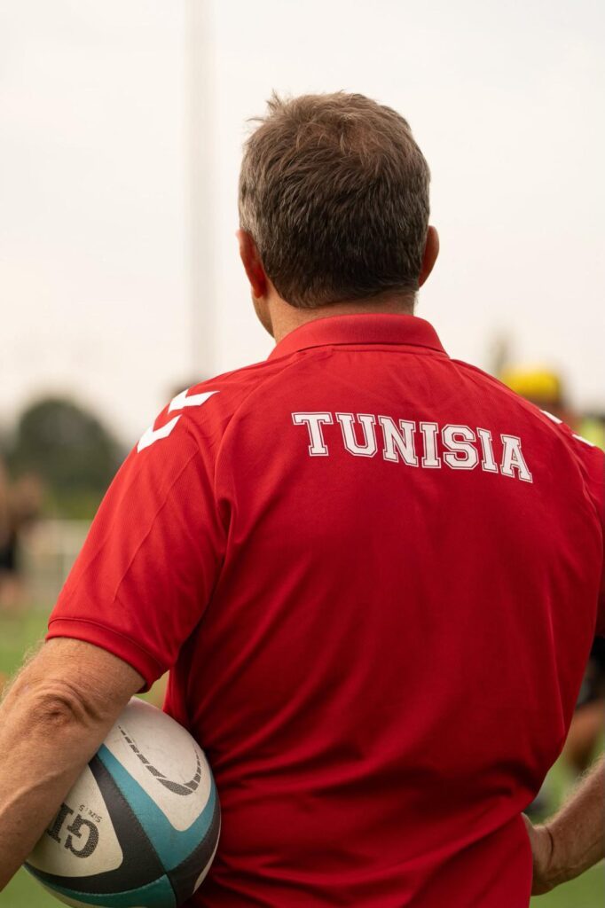 Christophe Hamacek seen from behind, ball under his arm, wearing a red polo shirt branded Tunisia